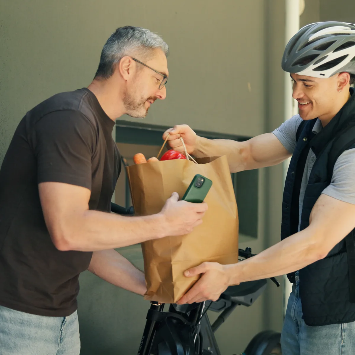 A bicycle courier handing groceries to a customer at their door