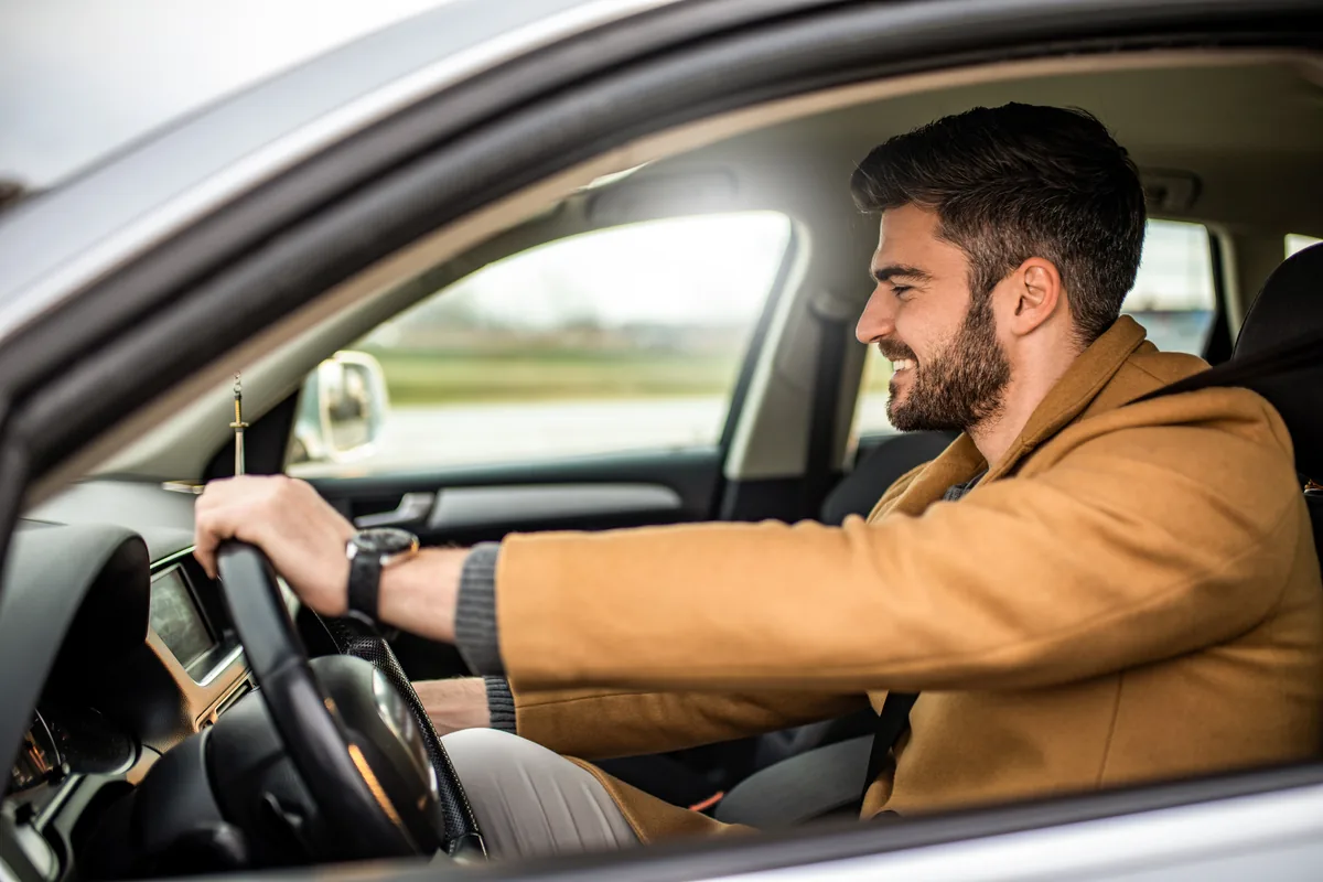 A rideshare driver smiling at the wheel of their car