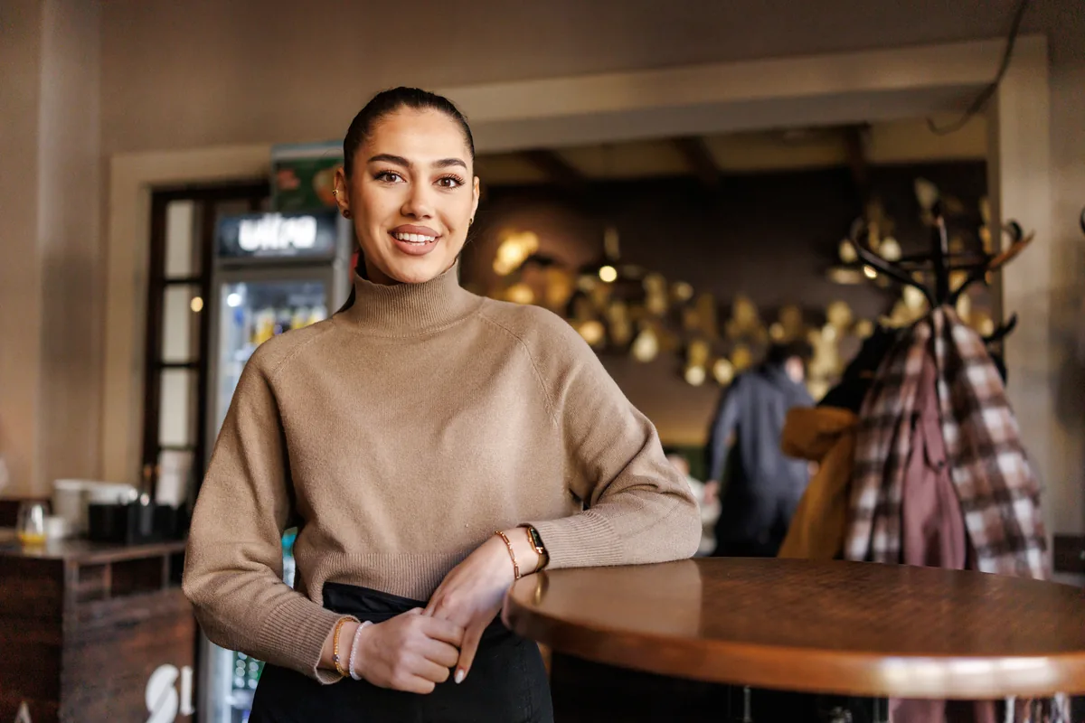 A restaurant owner standing behind the bar in her restaurant