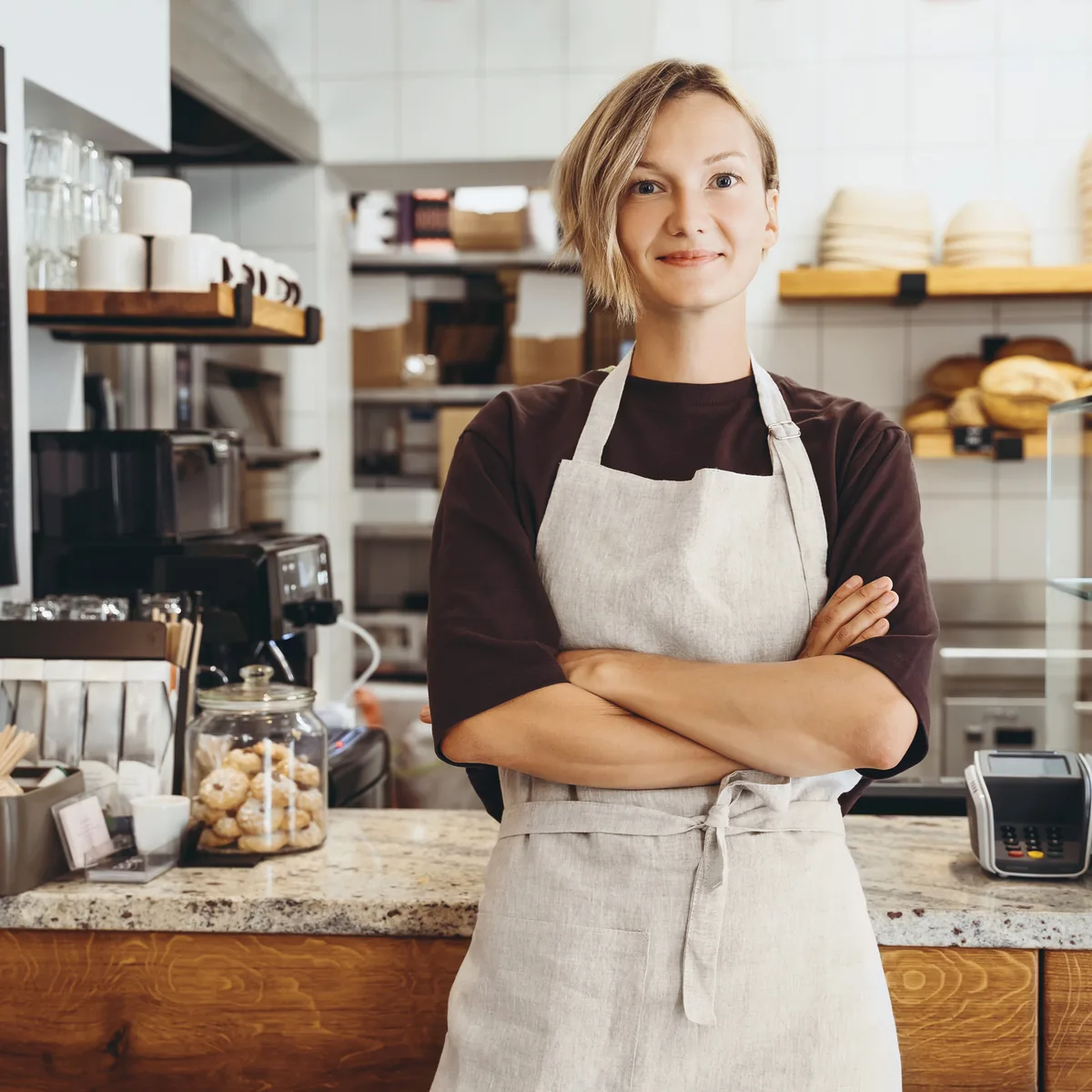 A café owner in an apron standing behind the counter